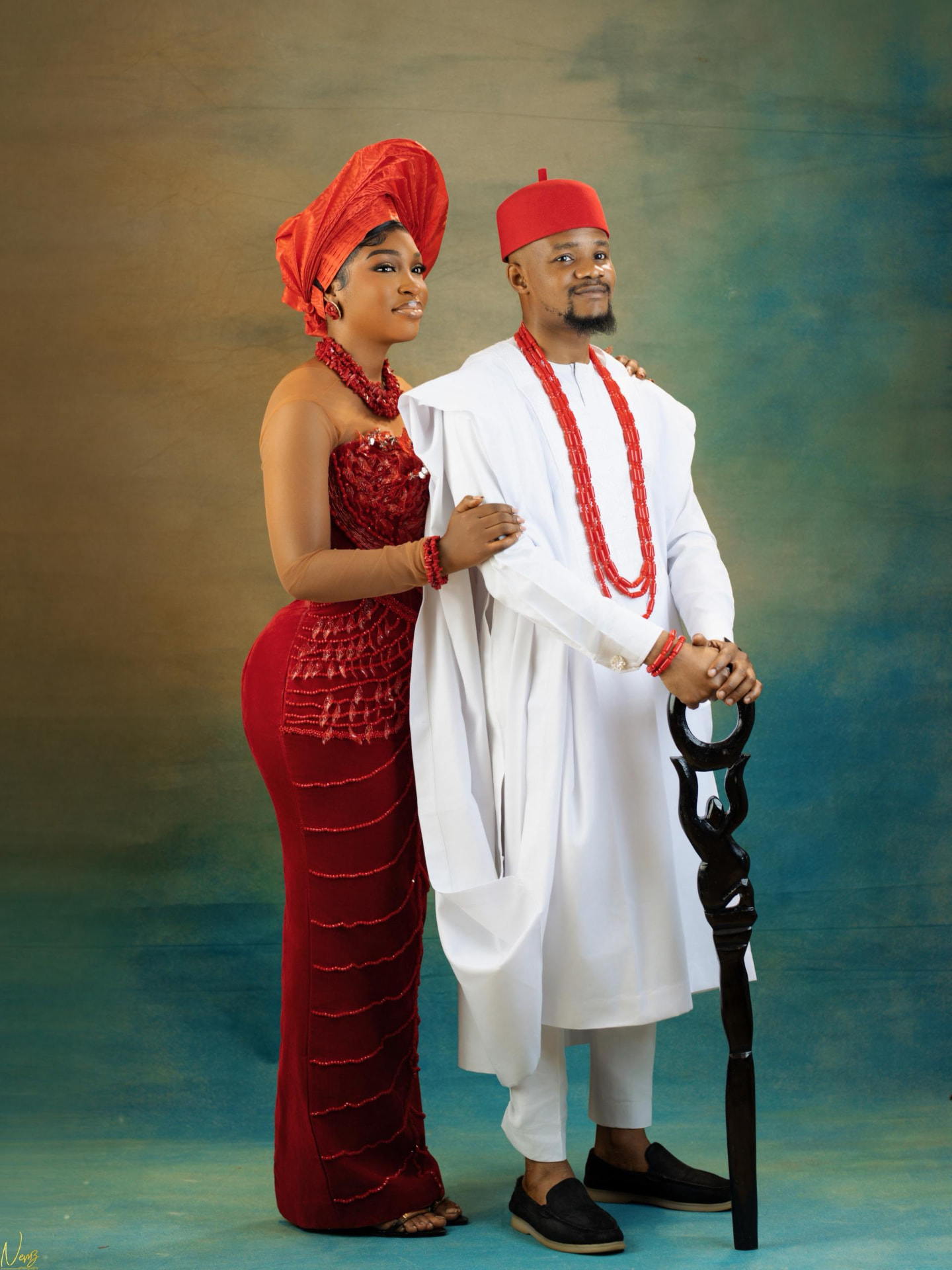 Kent and Iheoma in traditional Igbo attire, Iheoma in a red beaded gown and gele, Kent in white with coral beads